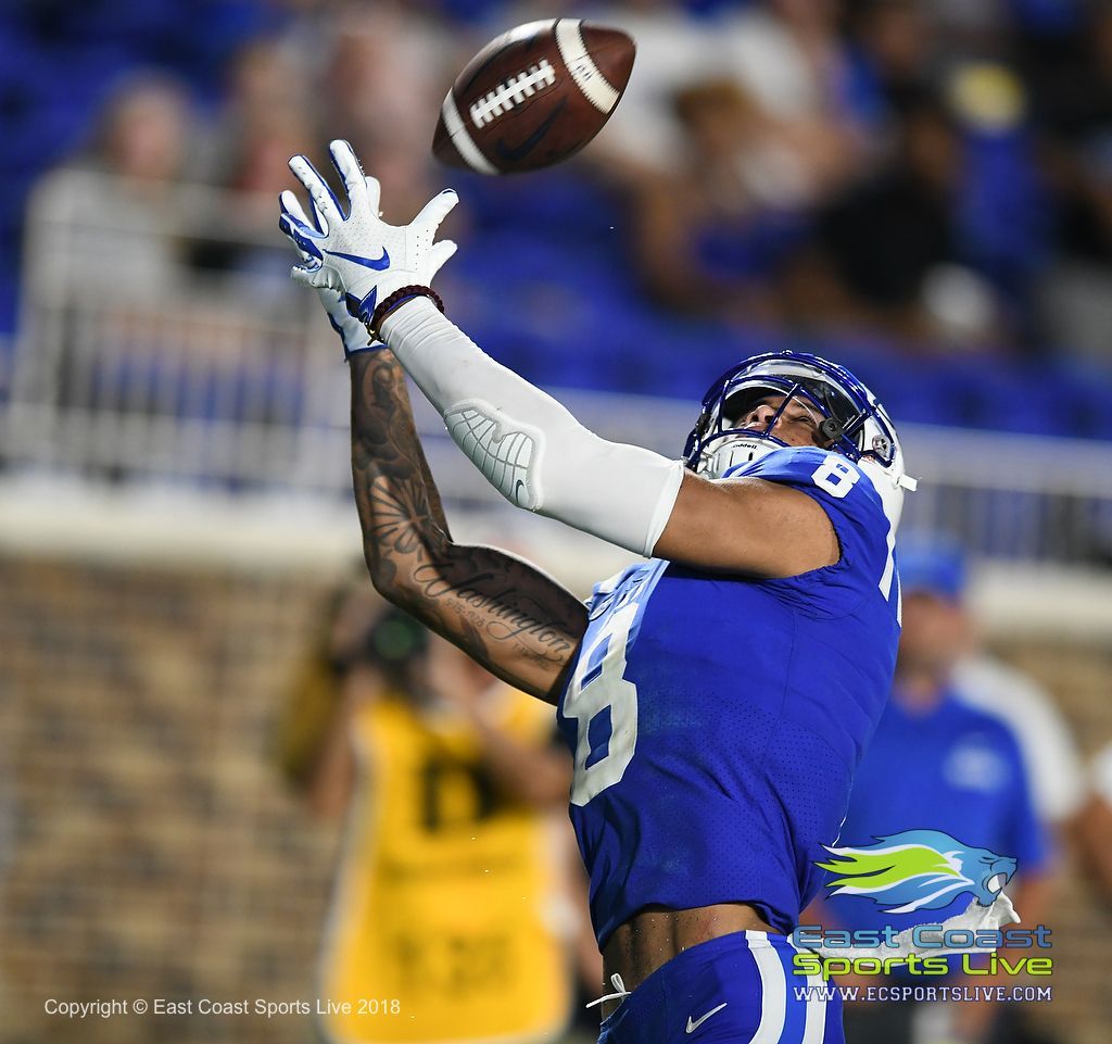 A football player with the number 8 on his jersey catches a ball