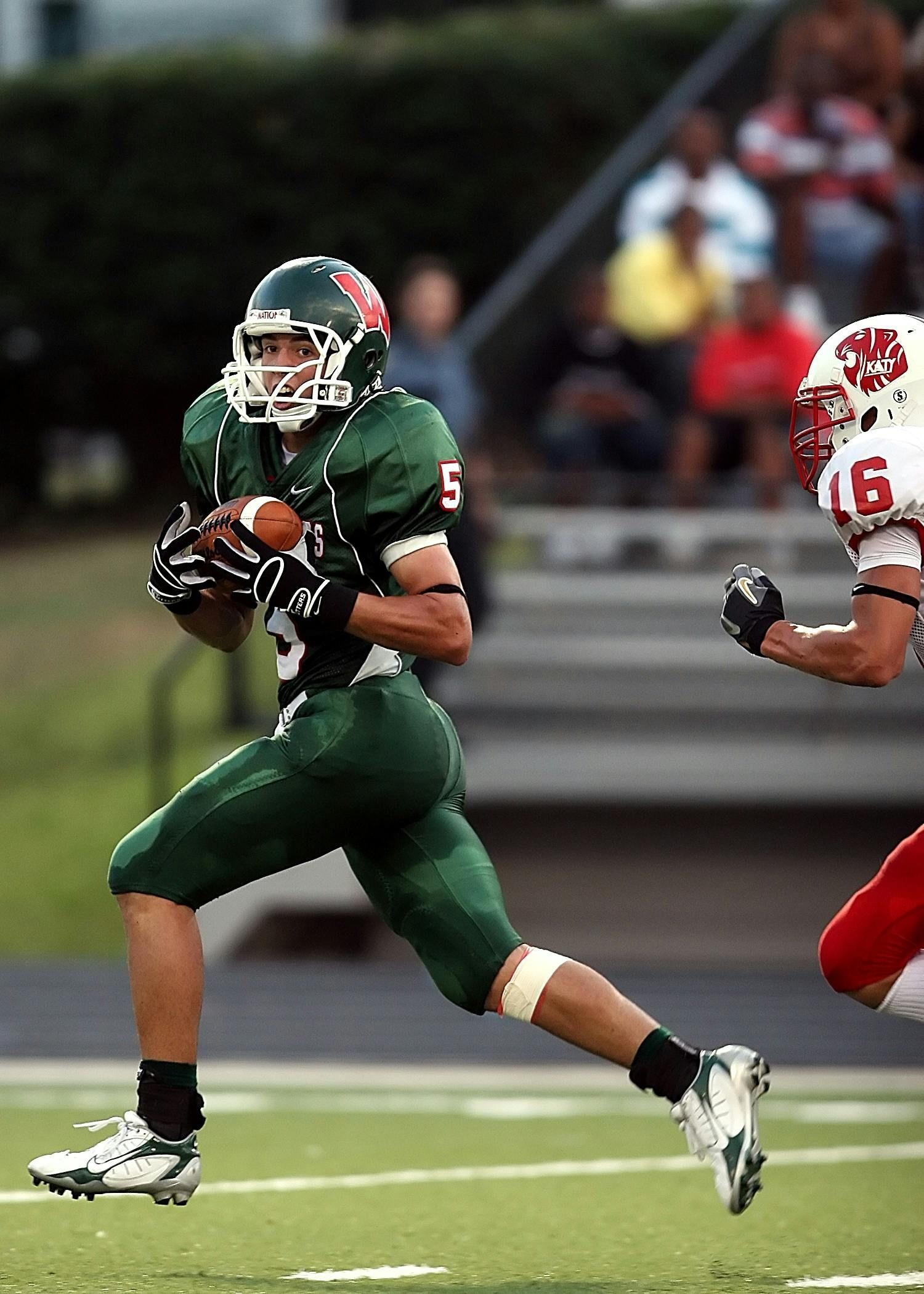 A football player with the number 5 on his jersey is running with the ball