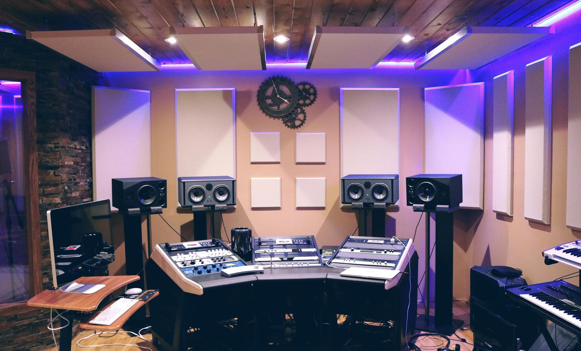 Recording studio with audio equipment, sound panels, and speakers. Lit in purple.