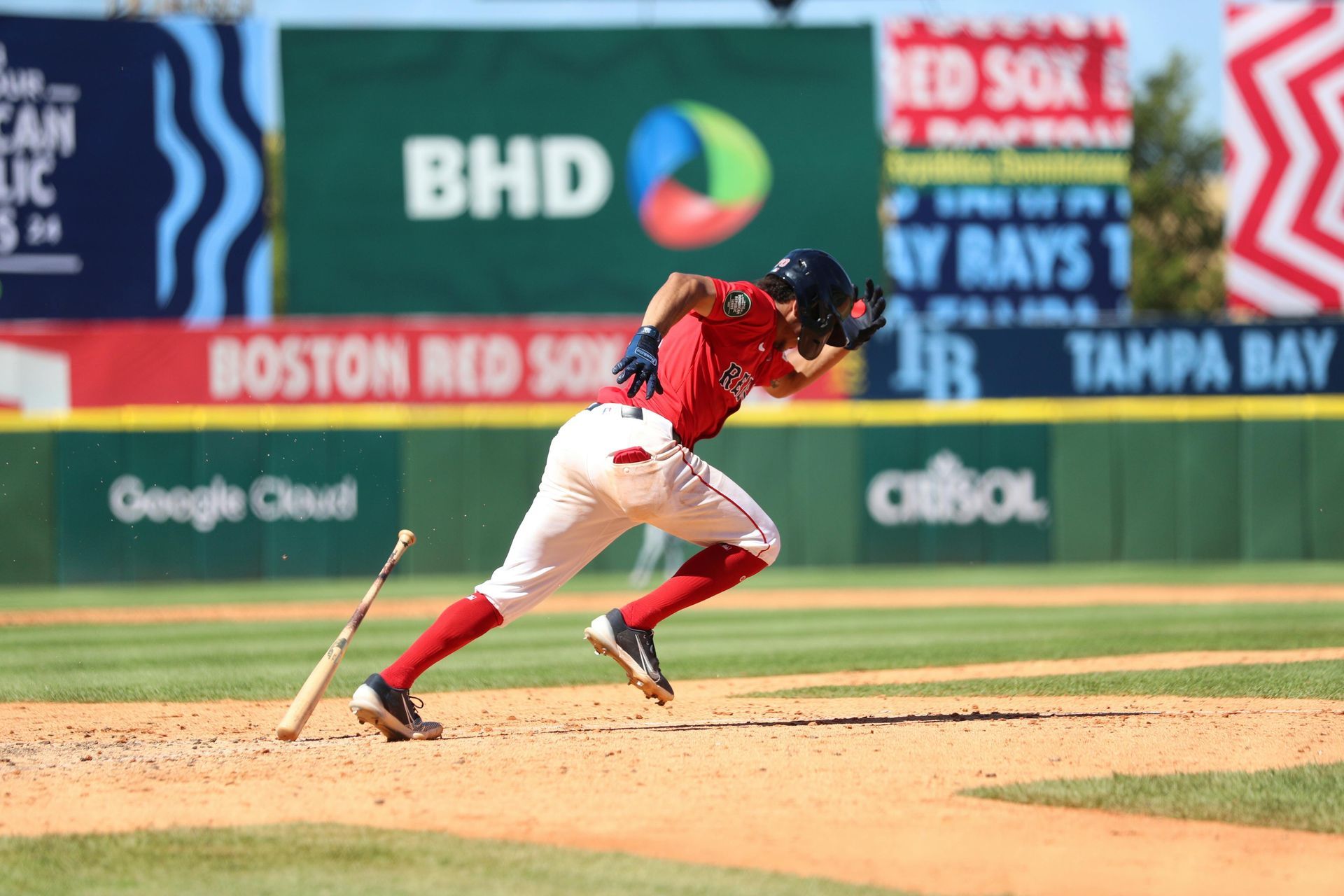 A baseball player is running towards home plate with a bat in his hand.