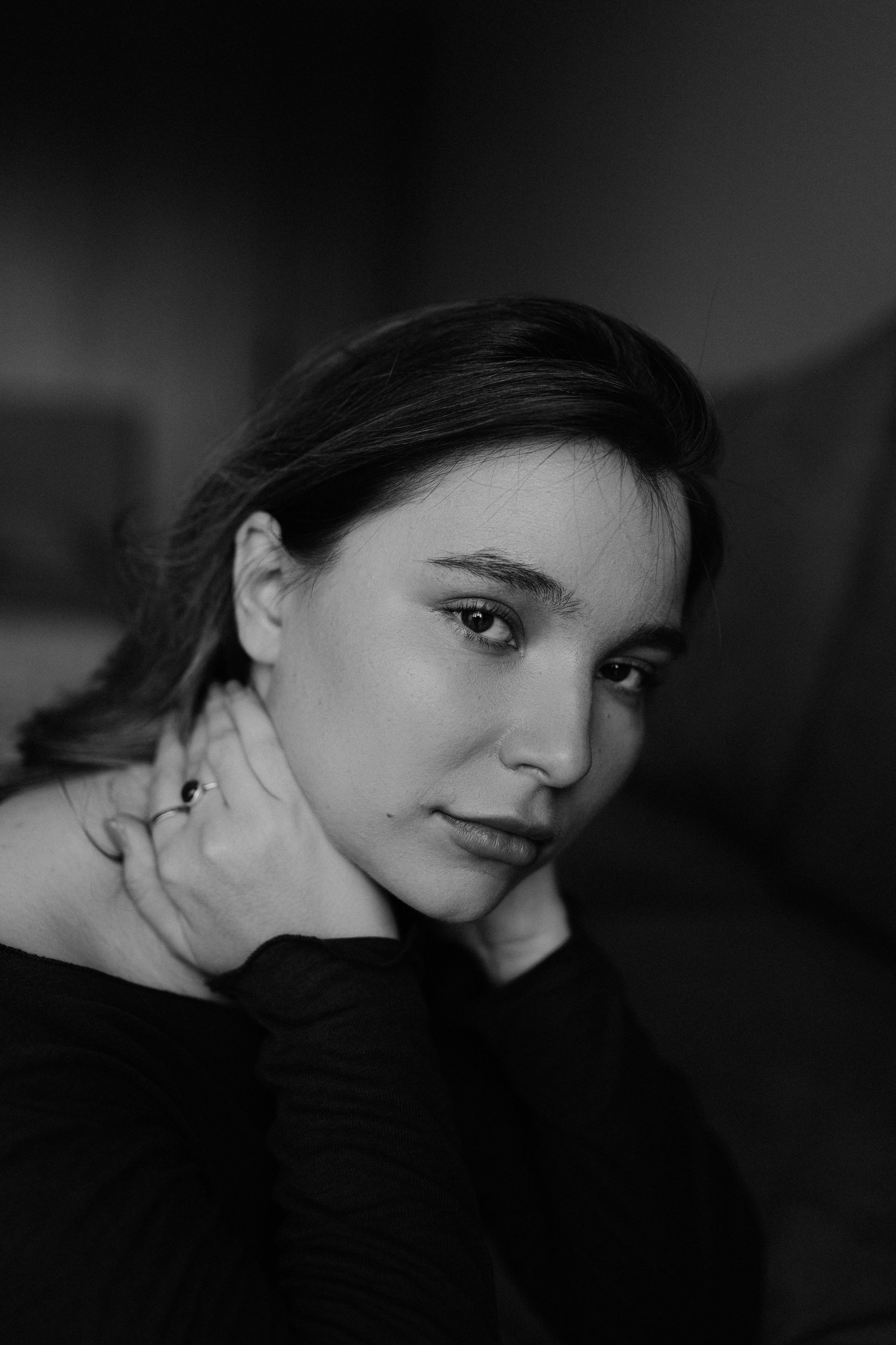 A woman is holding her neck in a black and white photo.