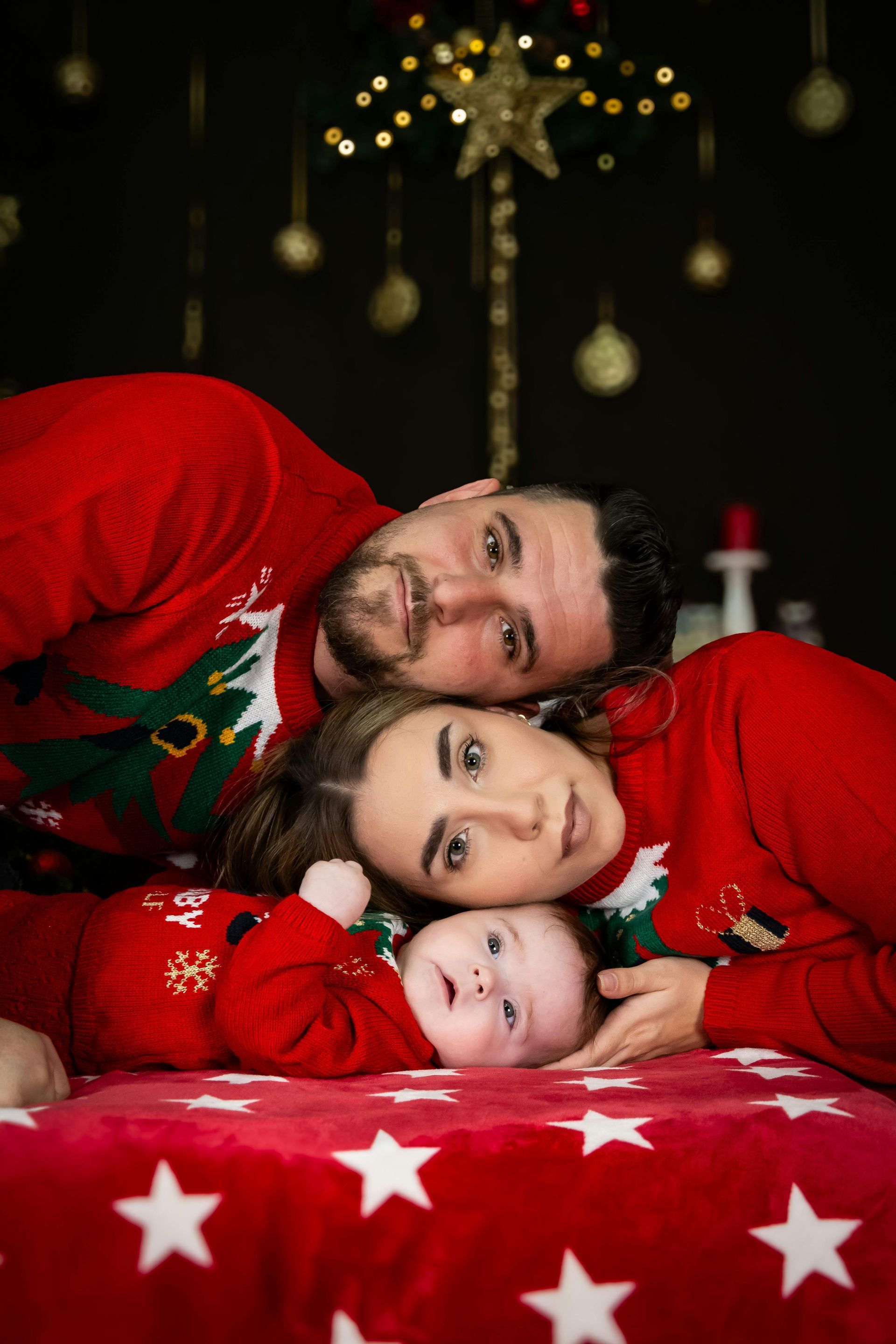 A family is posing for a picture in front of a christmas tree.