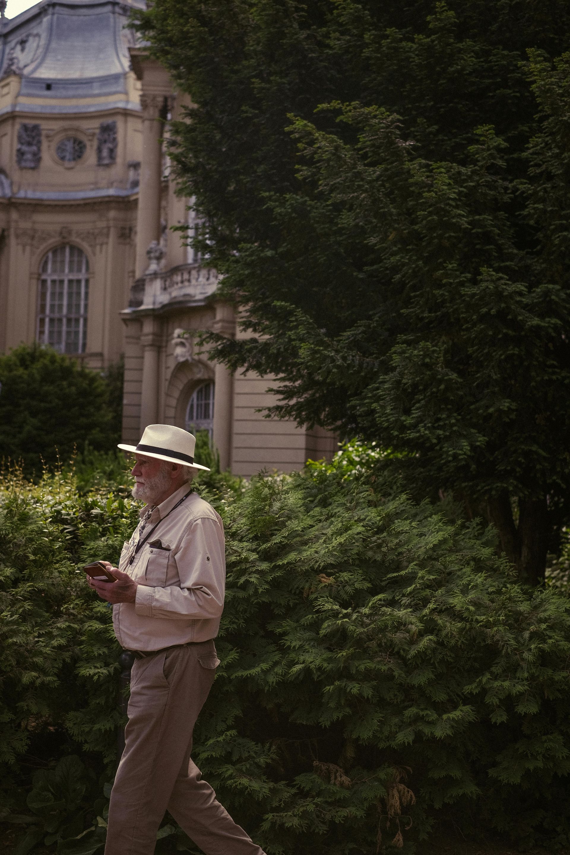 A man wearing a hat is walking in front of a building.