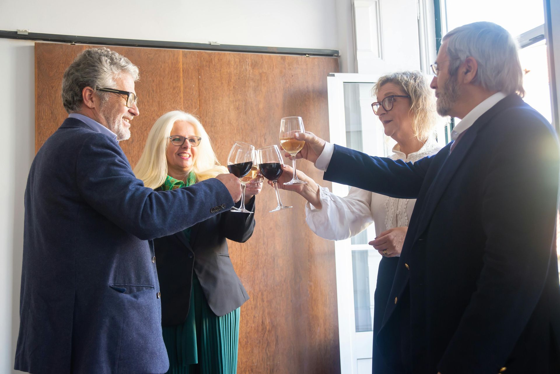 A group of people are toasting with wine glasses in a room.