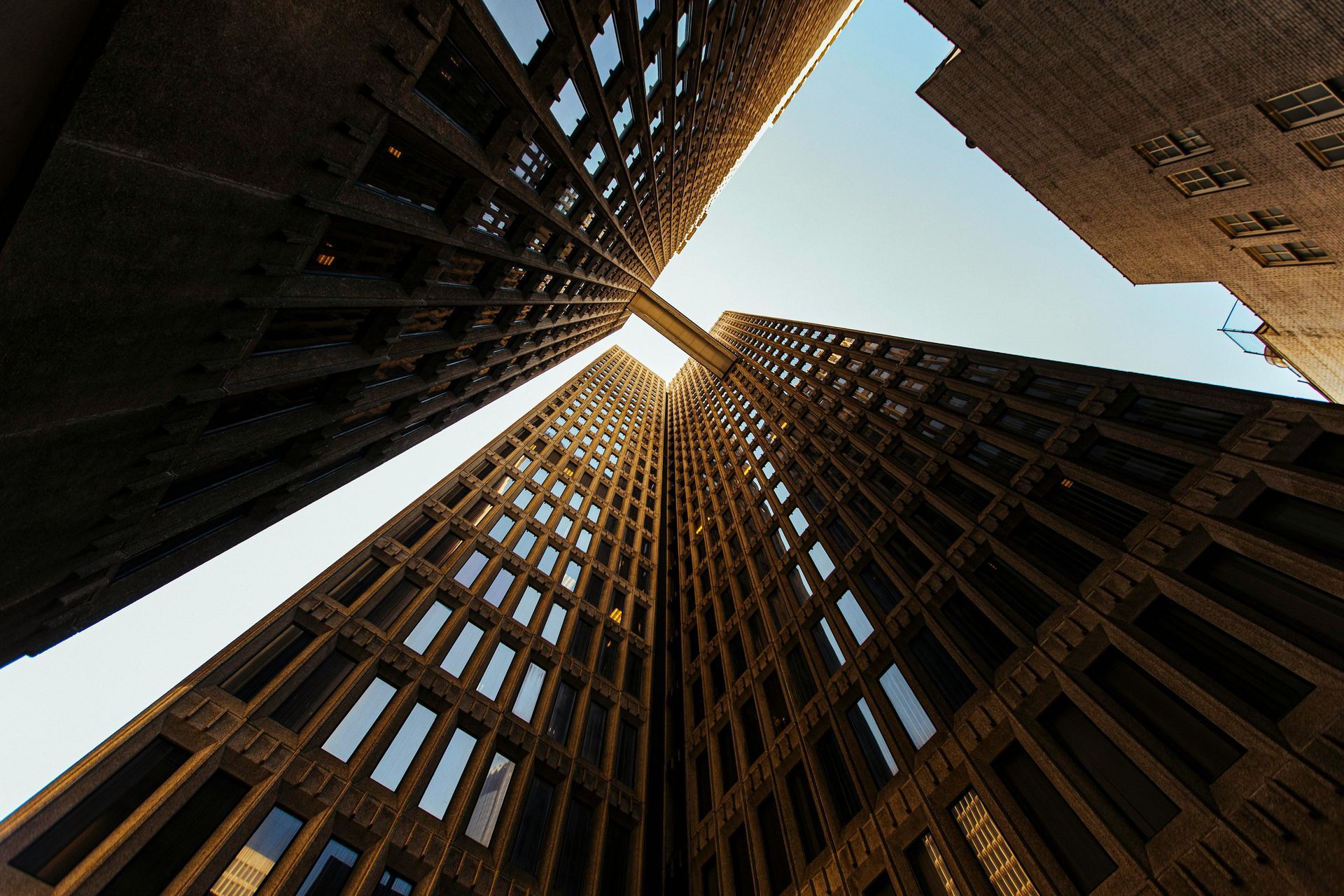 Looking up at tall brown brick buildings, a sliver of blue sky is visible.