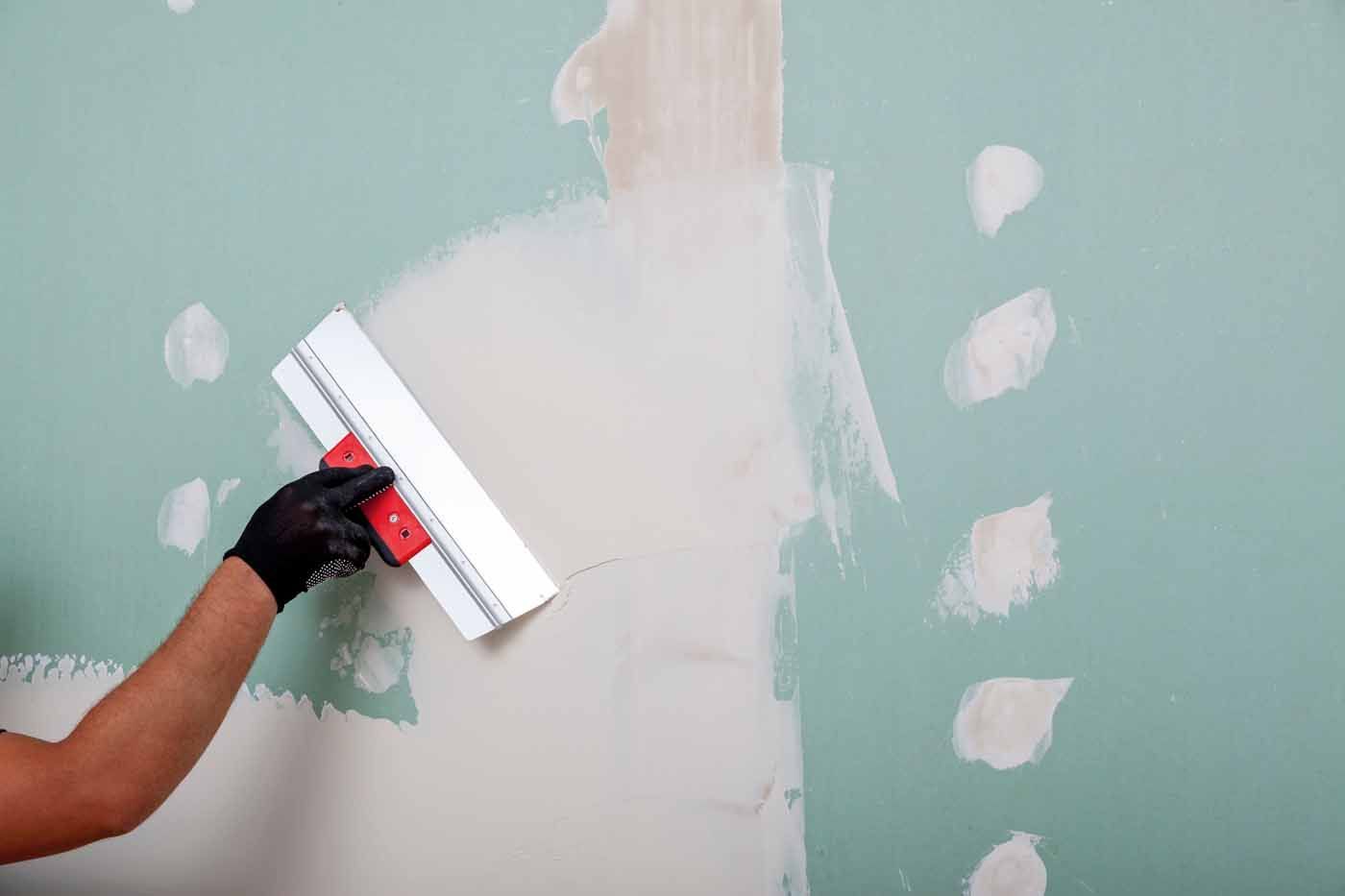 A person is plastering a wall with a spatula.