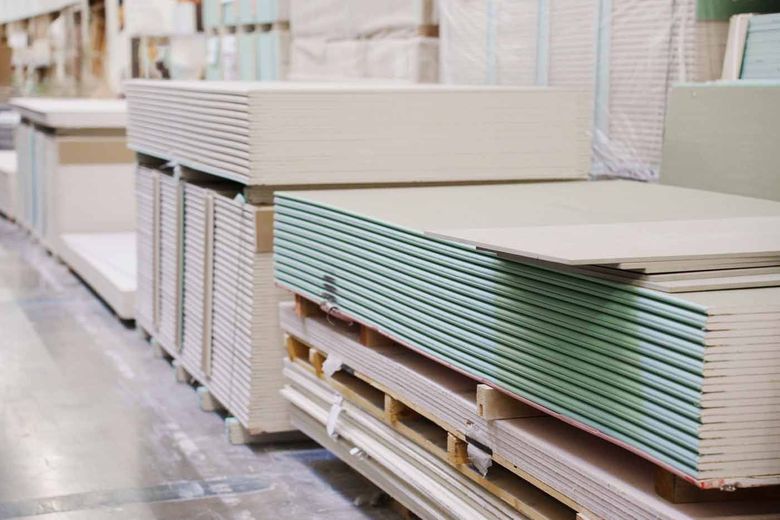 A warehouse filled with stacks of drywall sheets.