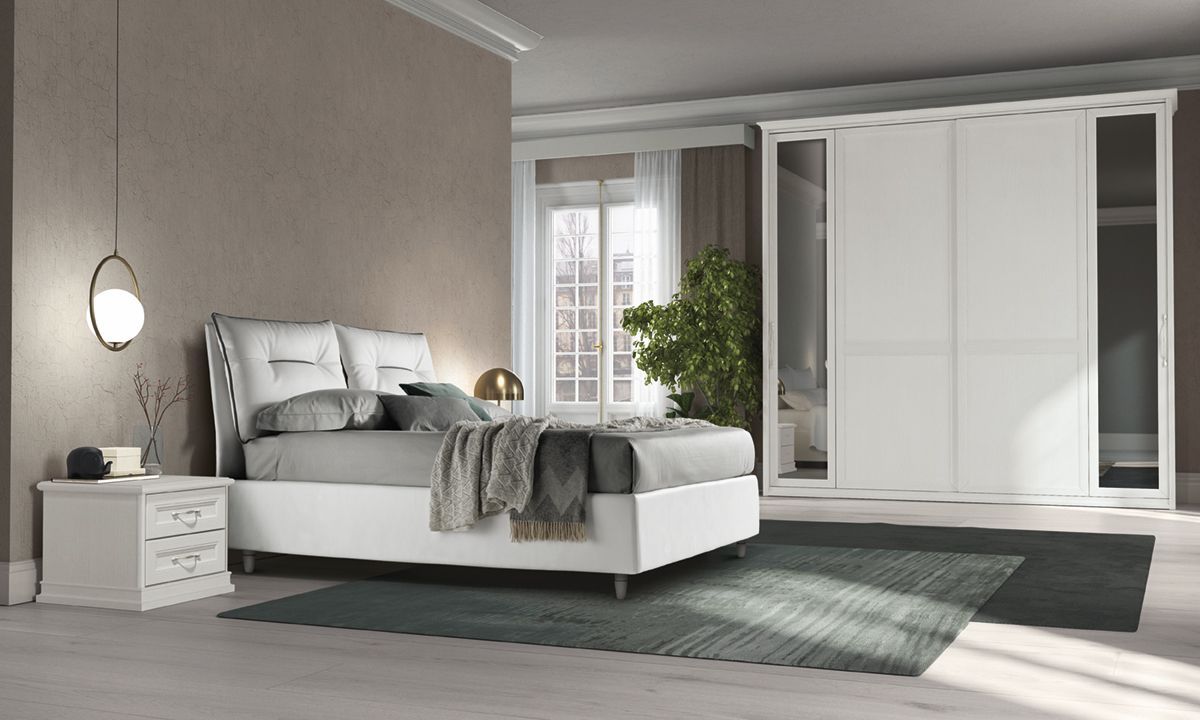 Camera da letto con mobili bianchi, letto, comodino, armadio con ante scorrevoli e tappeto verde.