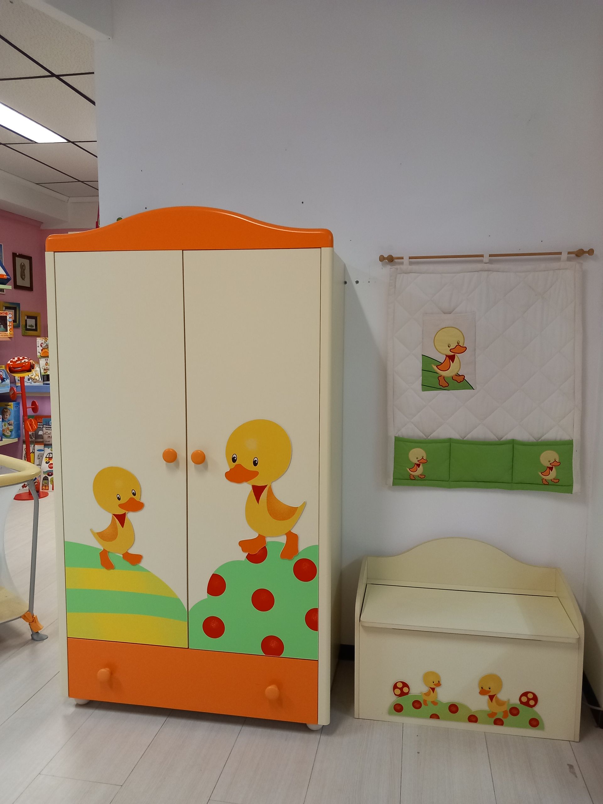 Set di mobili per la cameretta a tema anatre color crema e arancione: armadio, baule dei giocattoli e decorazioni da parete.