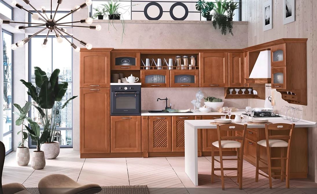 Una cucina ben illuminata, nei toni del marrone, con mobili in legno, un'isola con piano di lavoro bianco e ampie finestre.