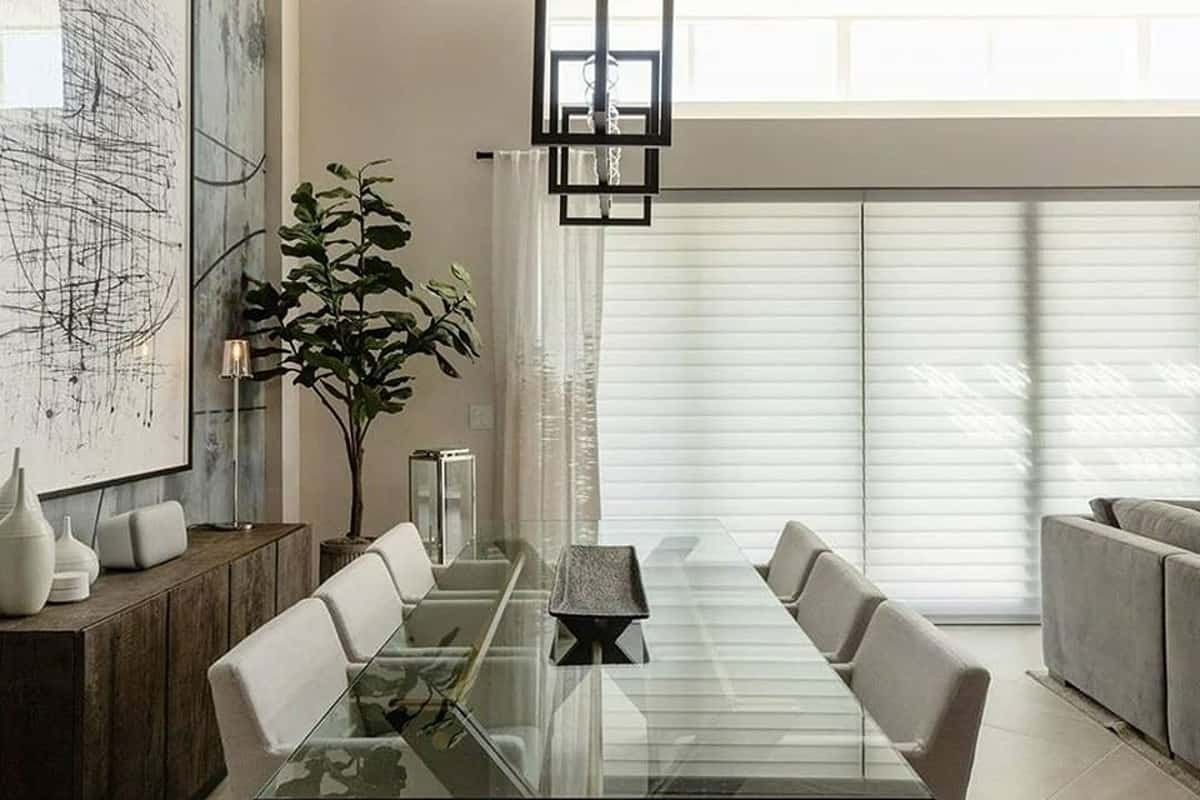 A dining room with a long glass table and white chairs.