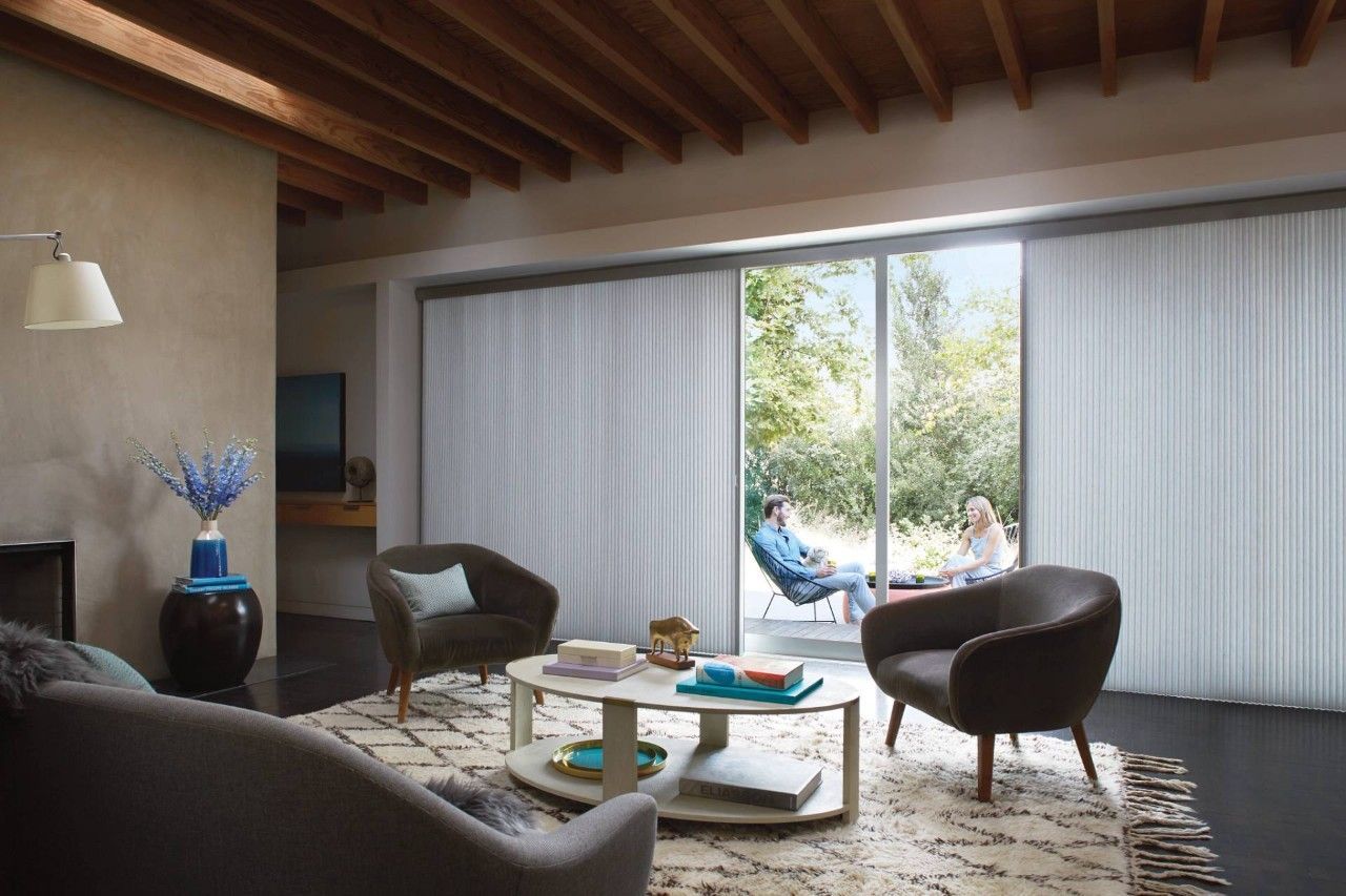 A living room with a sliding glass door and white vertical blinds.