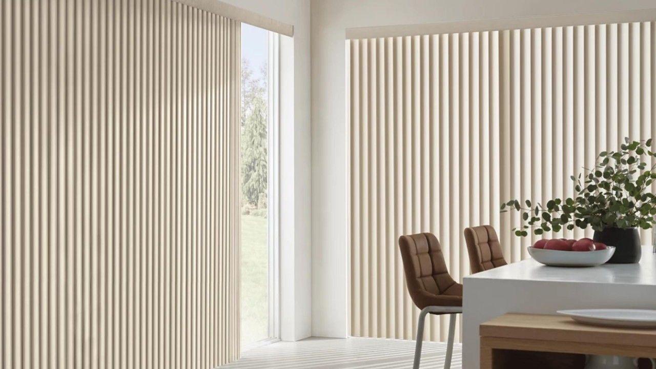 A kitchen with vertical blinds on the windows and a table and chairs.