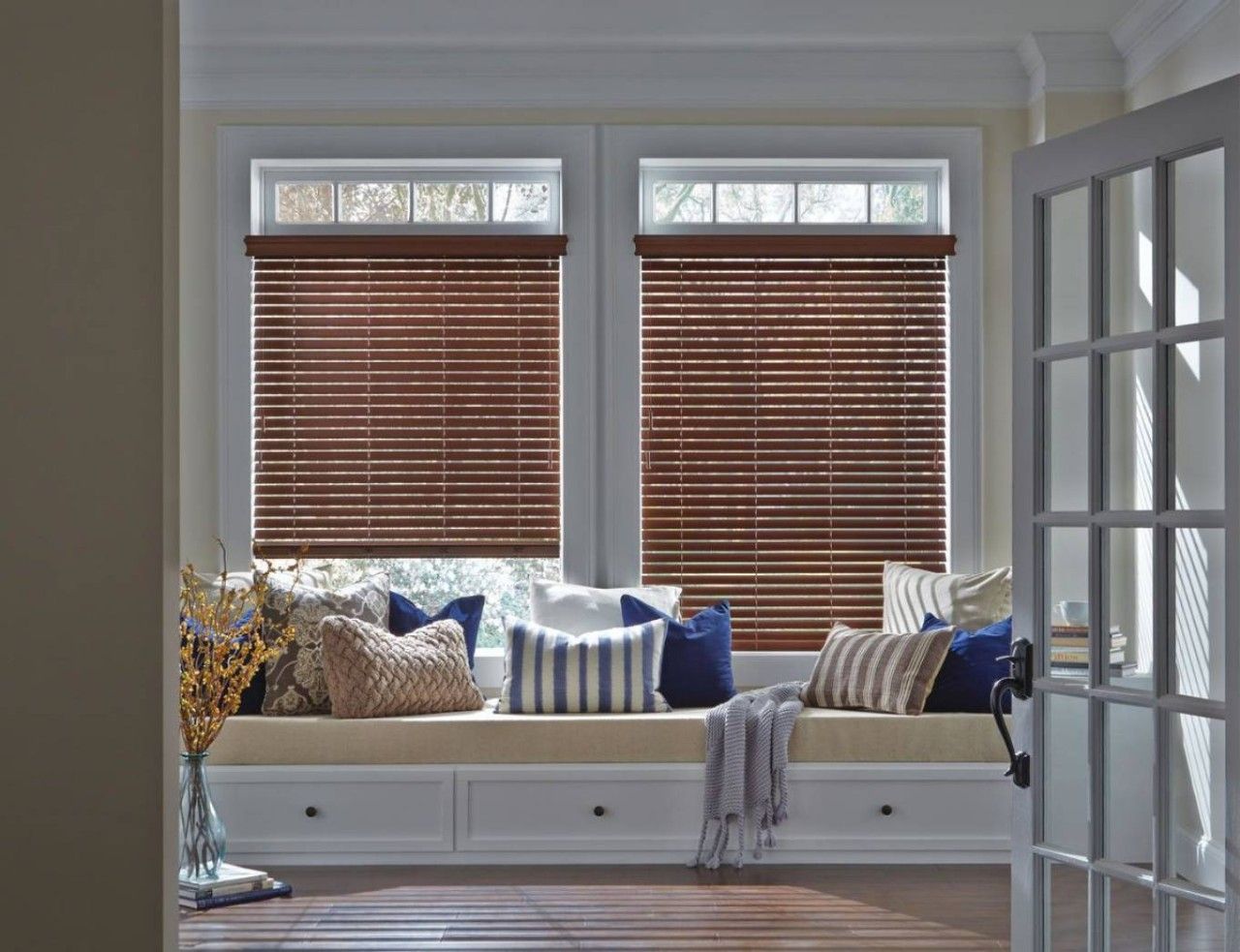 A living room with a window seat and wooden blinds.
