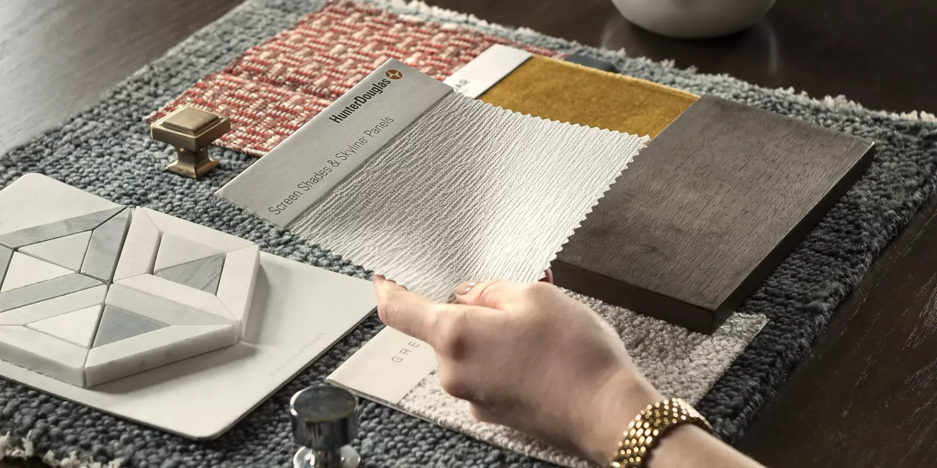 Hand holding Hunter Douglas Screen Shades & Skyline Panels swatch and samples