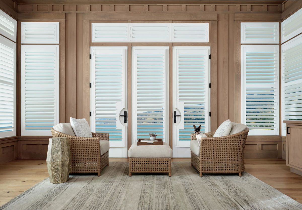 A living room with wicker furniture , a rug , and sliding glass doors.