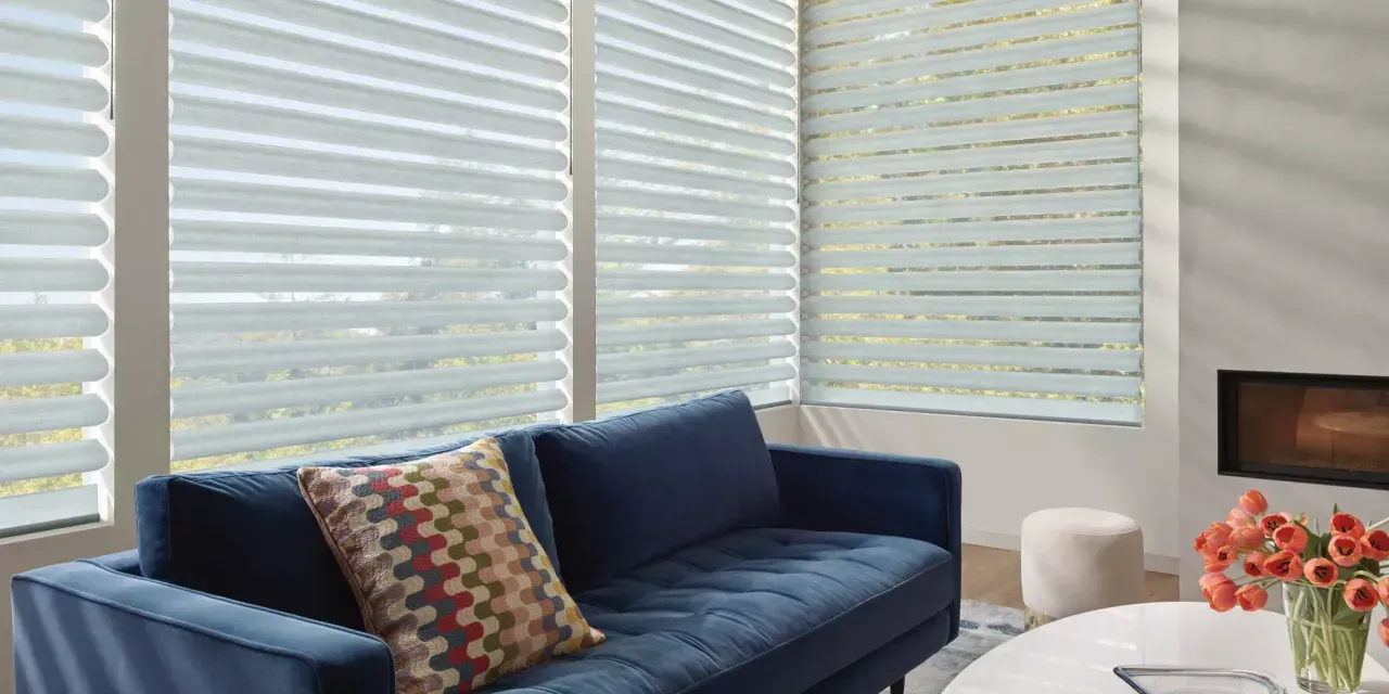 A living room with a blue couch and white blinds.