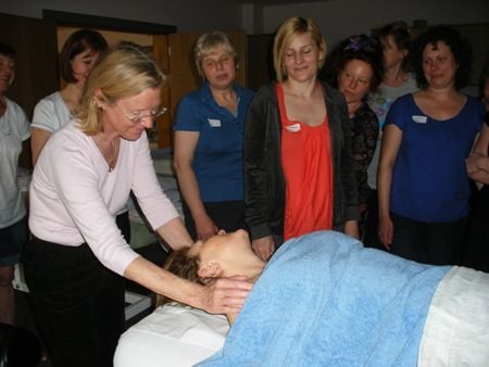 A group of women are standing around a woman laying on a massage table.
