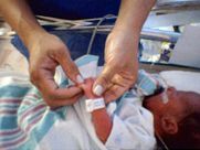 A person is holding a newborn baby in a hospital bed.