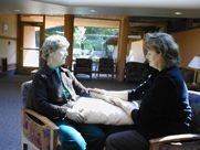 Two women are sitting in chairs talking to each other.