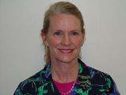 A woman in a floral shirt is smiling for the camera.