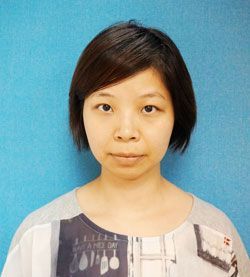 A woman with short hair is standing in front of a blue wall.