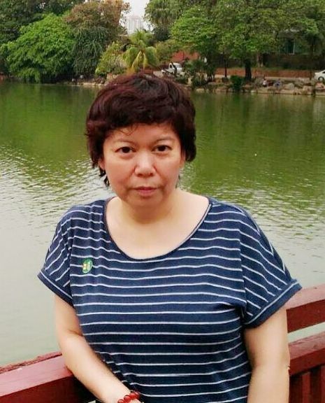 A woman in a striped shirt is sitting on a bridge overlooking a lake.
