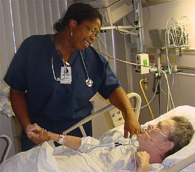 A nurse is talking to a patient in a hospital bed