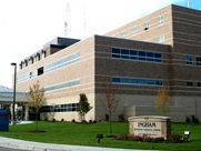 A large brick building with a lot of windows is sitting on top of a lush green field.