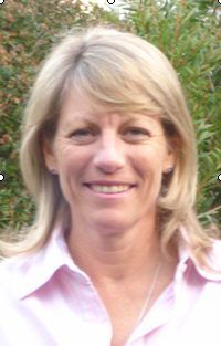 A woman in a pink shirt is smiling for the camera.