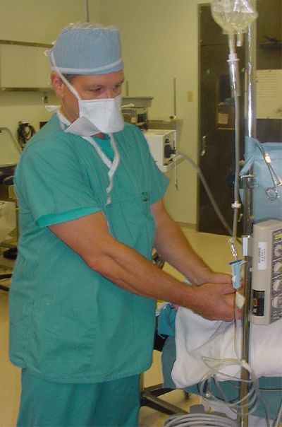 A surgeon wearing a mask and scrubs prepares a patient for surgery
