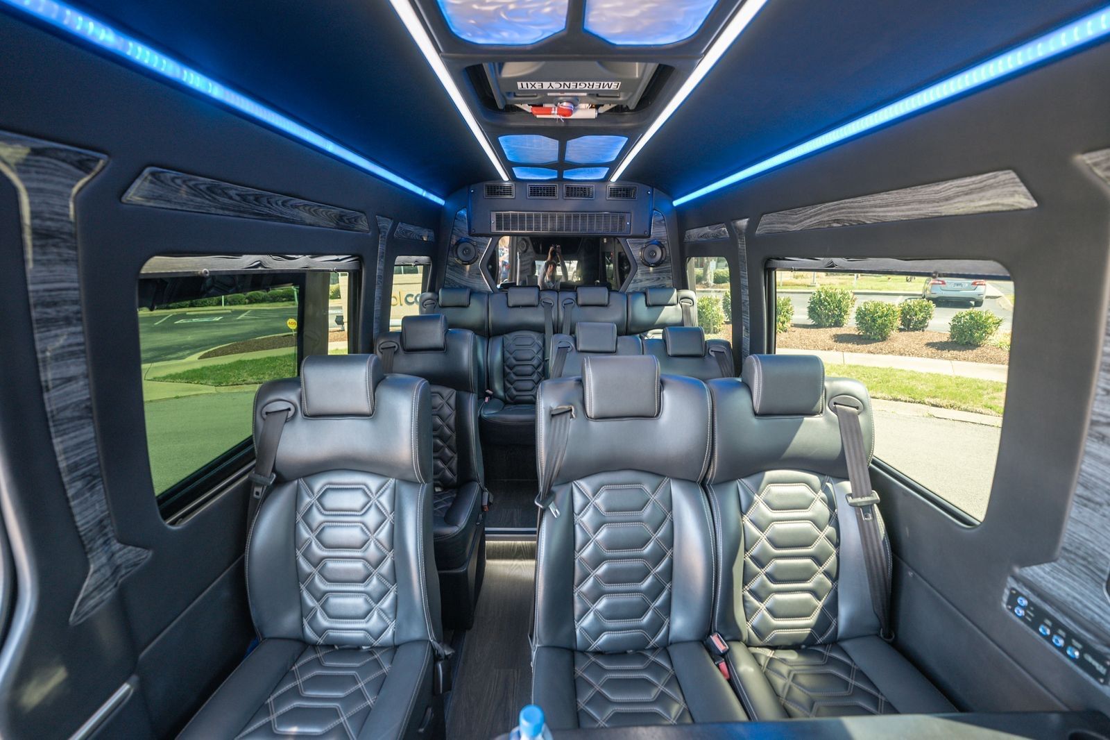 Black SUVs parked on a street in front of a modern building with a clear glass facade. Evening setting.