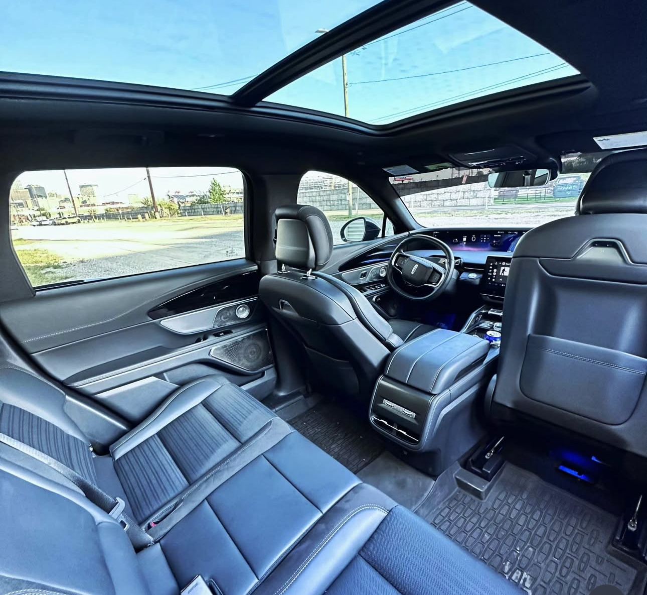 Four black SUVs parked at night, downtown buildings in the background.
