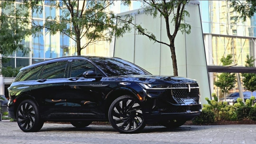 Black Lincoln Corsair SUV parked in front of a modern building with trees.