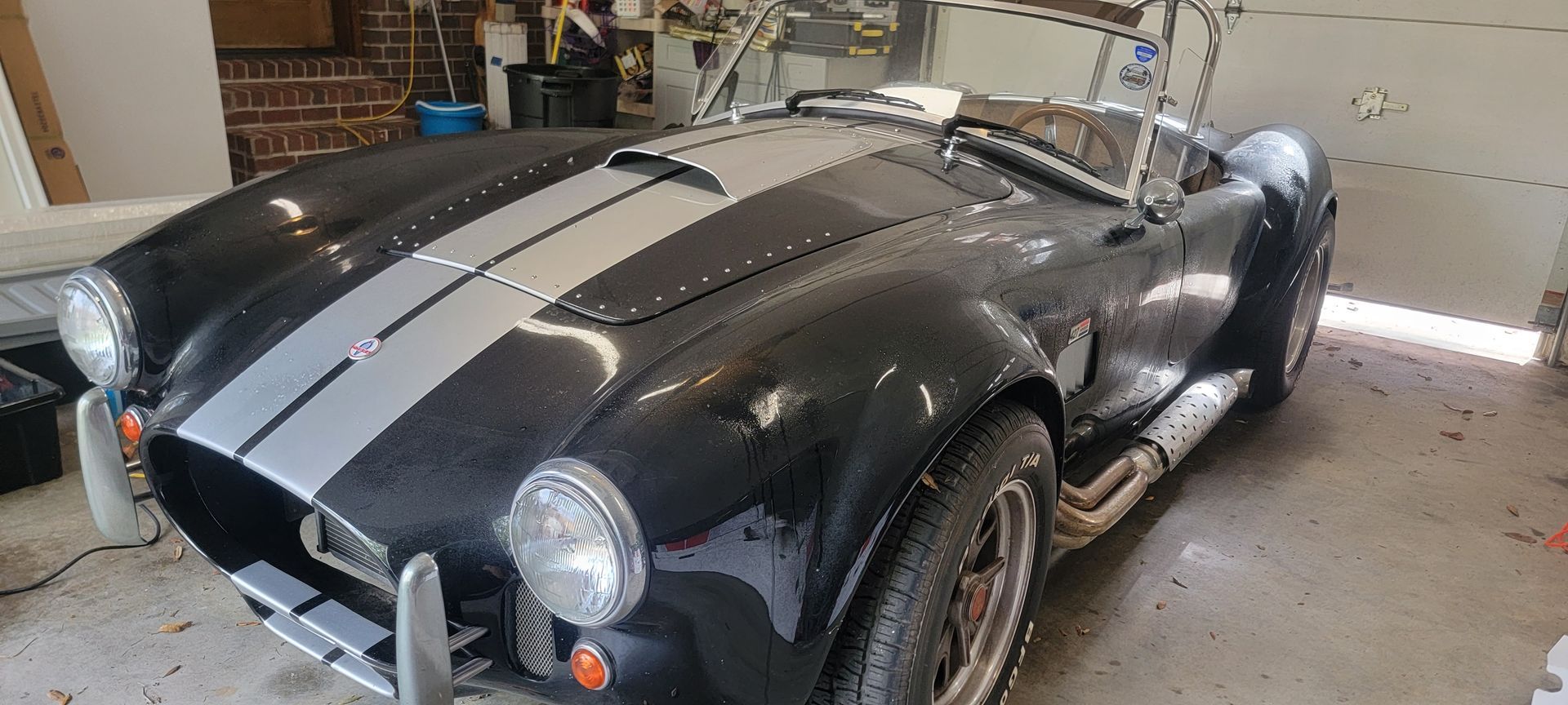 A black and silver sports car is parked in a garage.