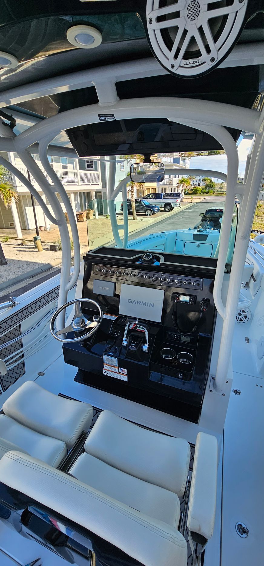 The cockpit of a boat with white seats and a steering wheel.