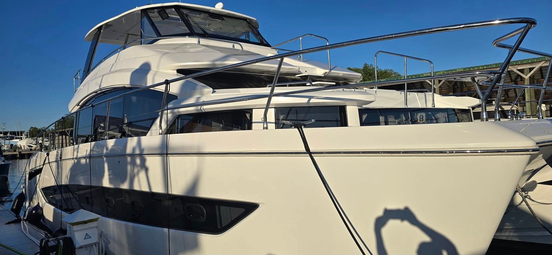 A large white yacht is docked in a marina.