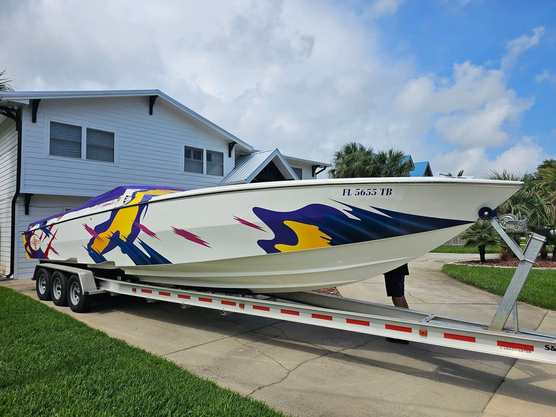 A boat is sitting on a trailer in front of a house.