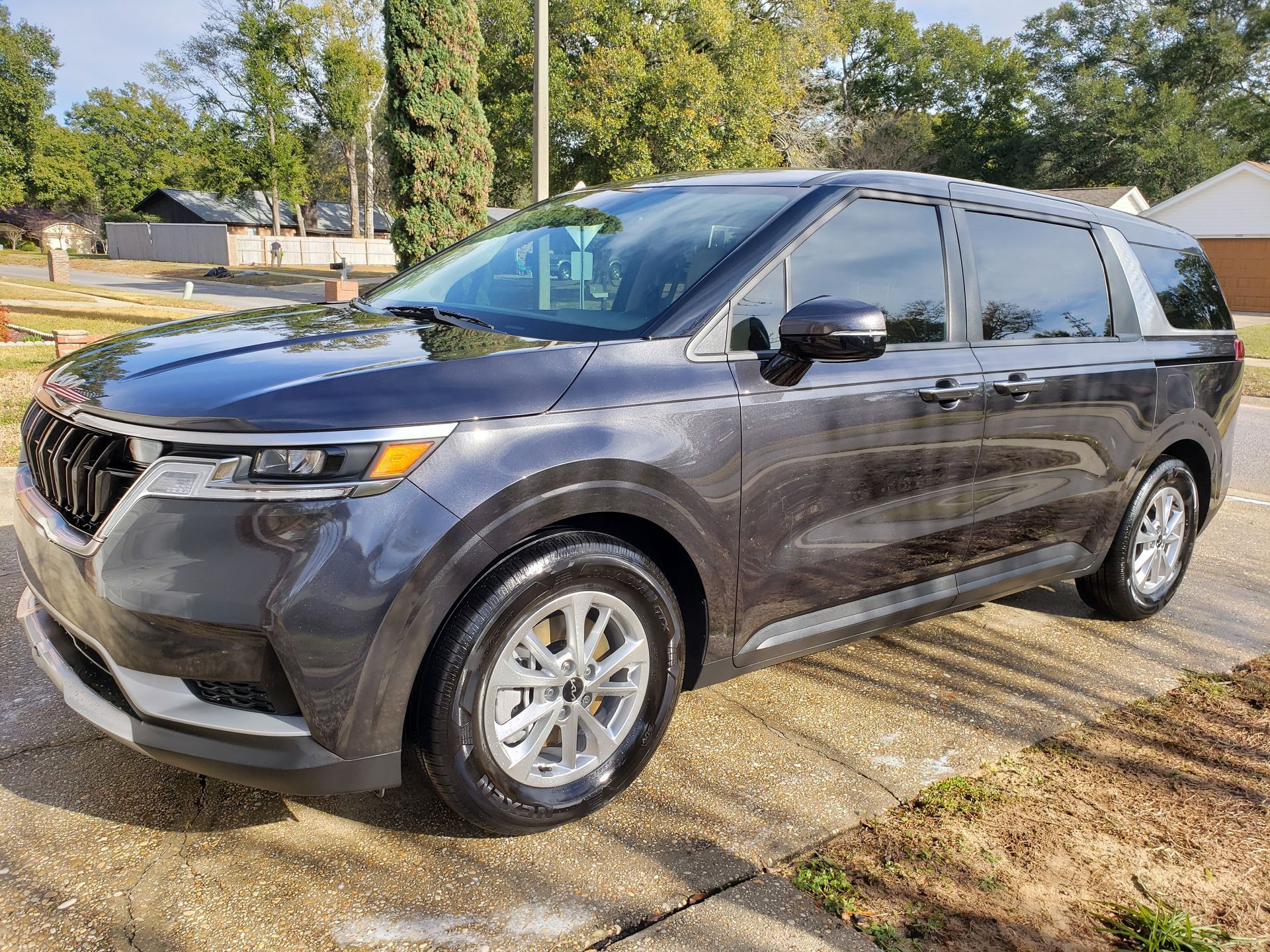 A black minivan is parked on the side of the road.