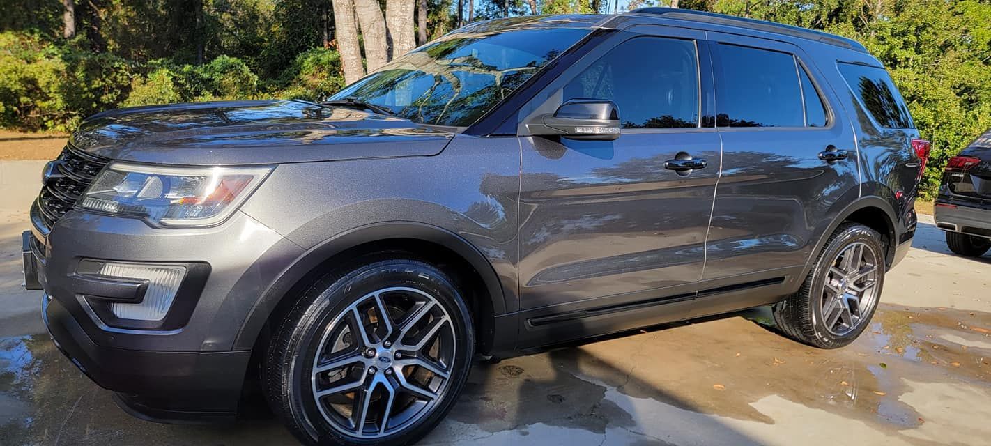A gray ford explorer is parked in a parking lot.