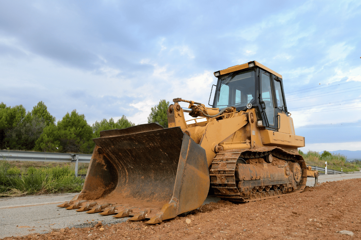 Yellow bulldozer on a construction site, cloudy sky.