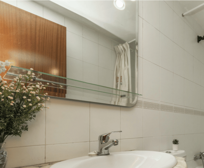Bathroom with white sink, tiled walls, and a large mirror.
