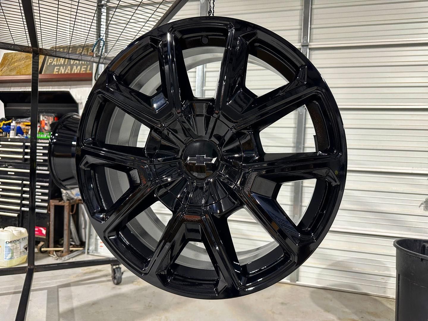 Black car wheel hanging from a hook.