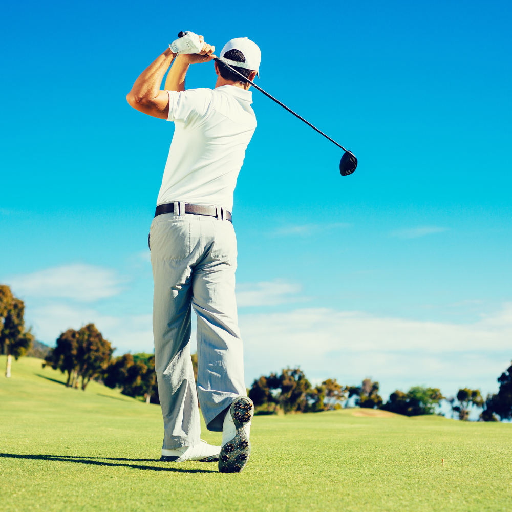 golfer has hit a ball with his driver on the fairway, clear blue sky.