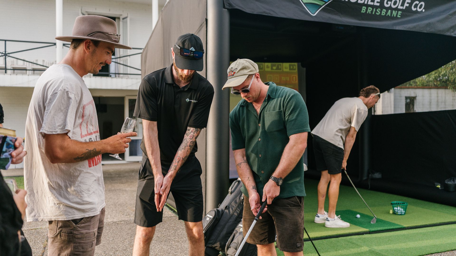 golf club resting behind the golf ball on the grass, ready to hit.