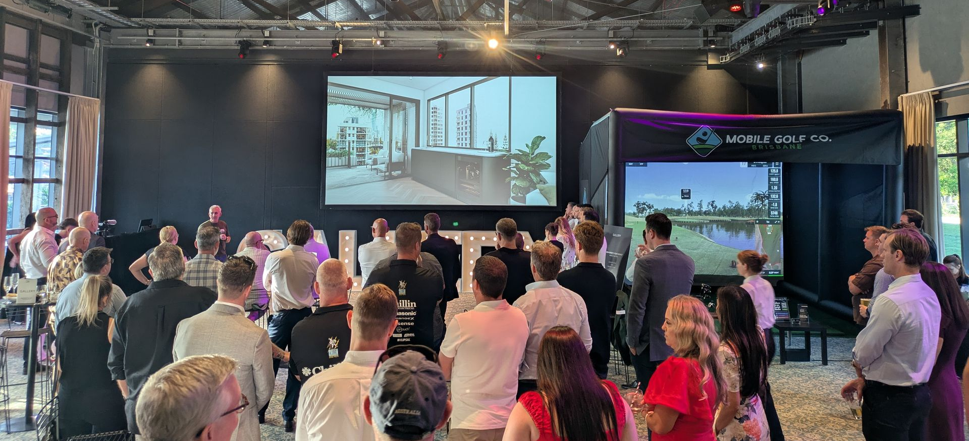 Employees at a corporate event raise their glasses to a successful golf simulator event.