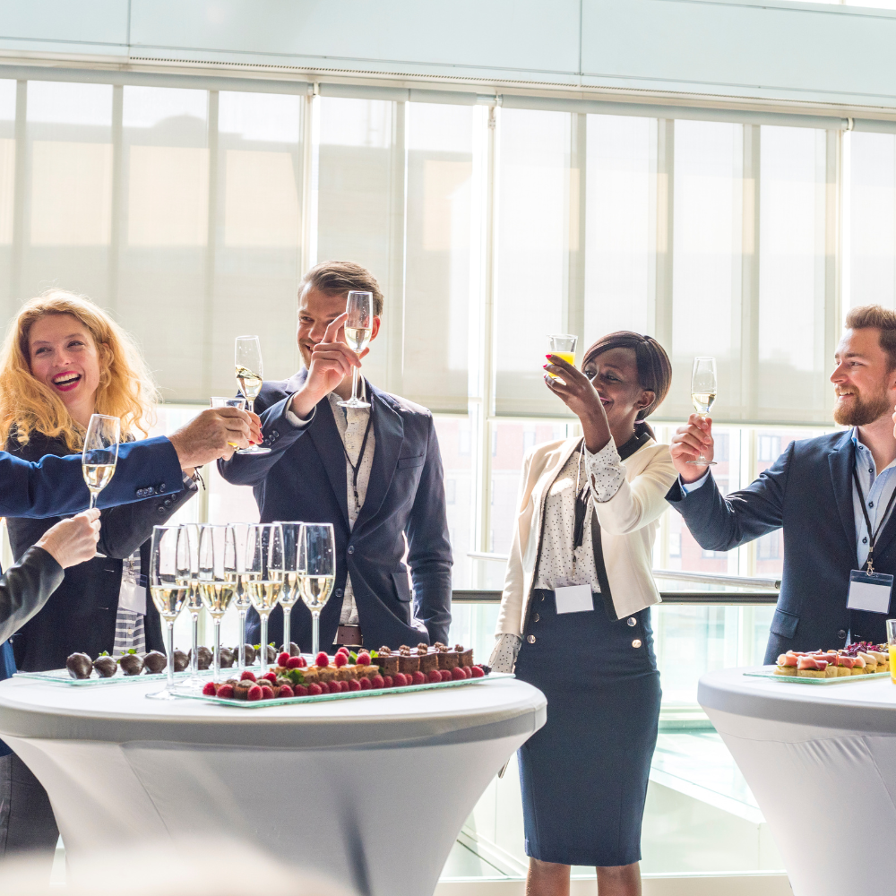 Employees at a corporate event raise their glasses to a successful golf simulator event.