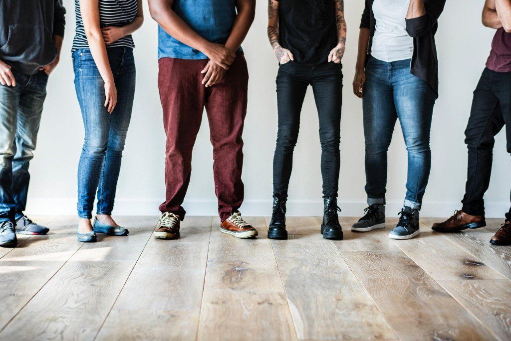 A group of people standing next to each other on a wooden floor.