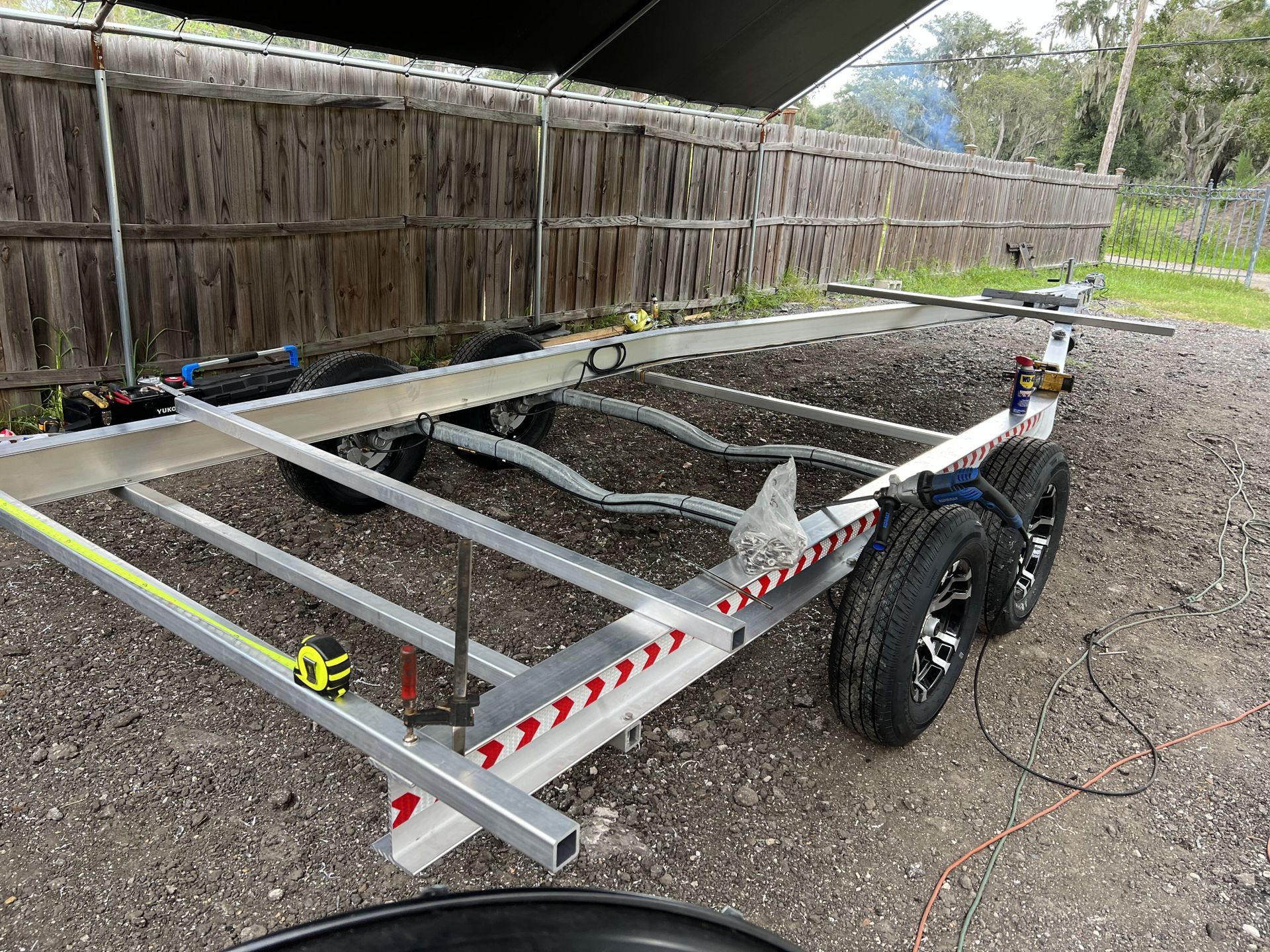 A trailer is sitting on the ground next to a wooden fence.