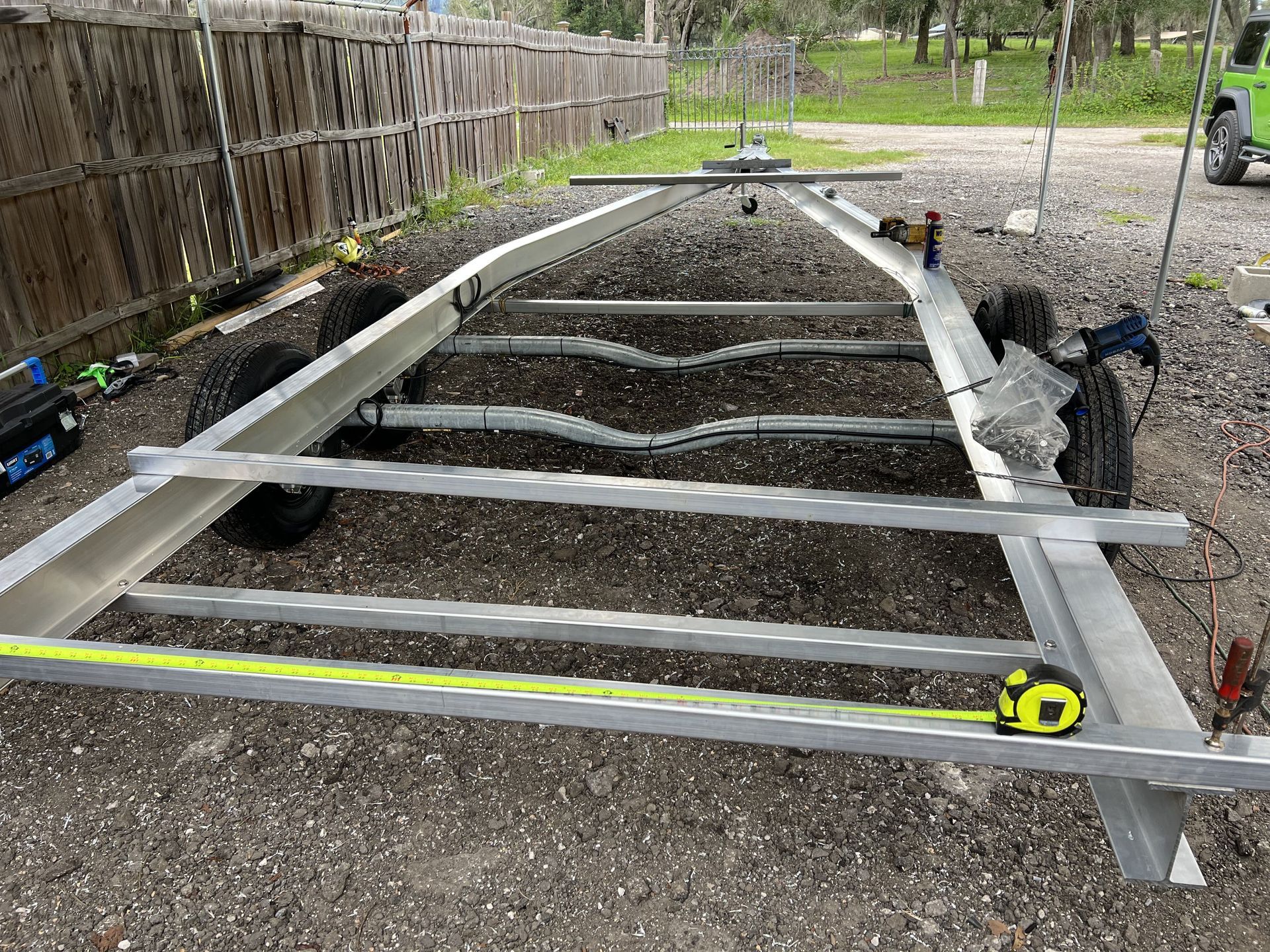 A metal trailer is sitting on the ground next to a tape measure.